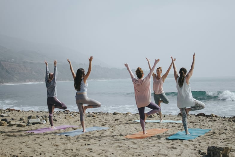 ragazze in spiaggia praticano yoga vicino alla riva del mare | Justbob