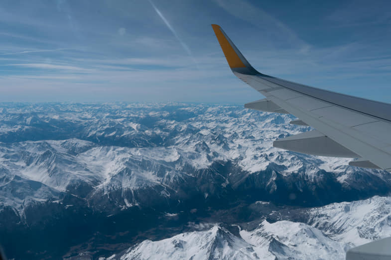 Il volo di un aereo fotografato da un passeggero, veduta dall'alto di un panorama innevato e della coda dell'aereo | Justbob