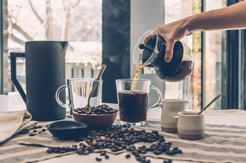 Una persona che versa in un bicchiere del caffè fatto in casa | Justbob